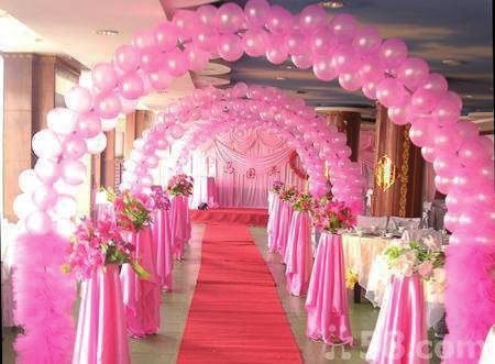Pink balloon arches along a red carpet